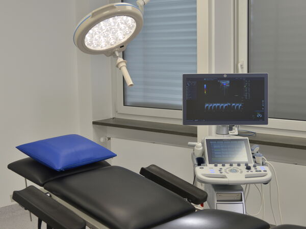 Moderner Operationssaal mit zentraler Liege, umgeben von medizinischen Geräten.